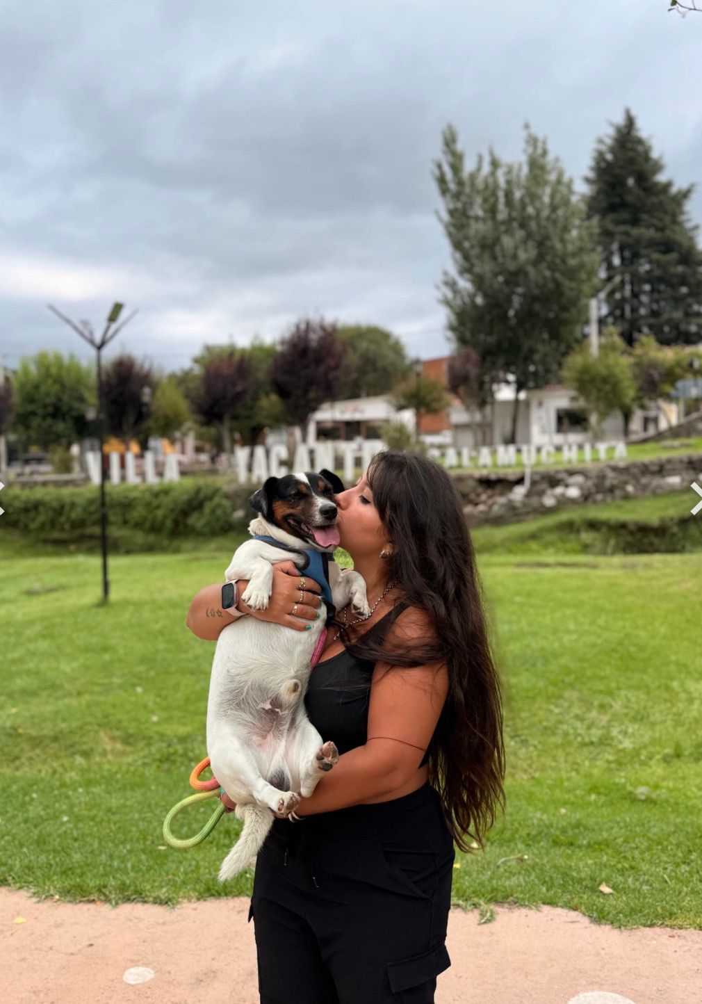 Sofia kissing a happy Jack Russell terrier in a park