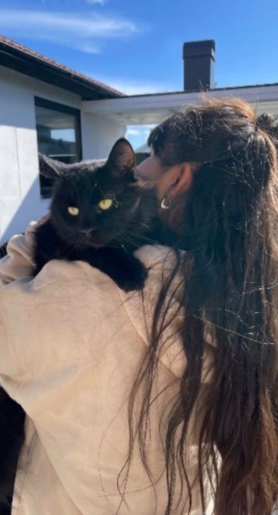 Sofia holding a black cat outdoors on a sunny day