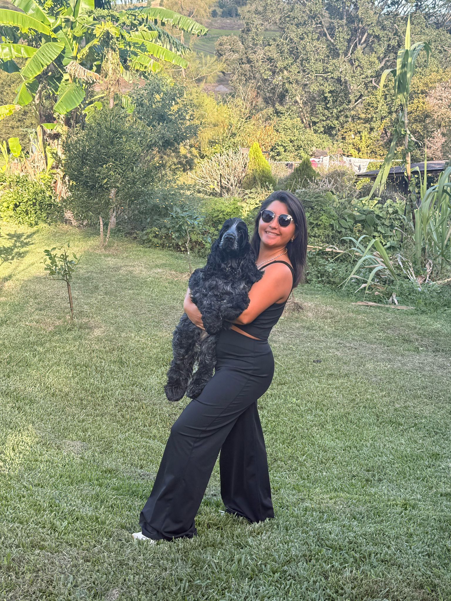 Sofia holding a black cocker spaniel in a garden