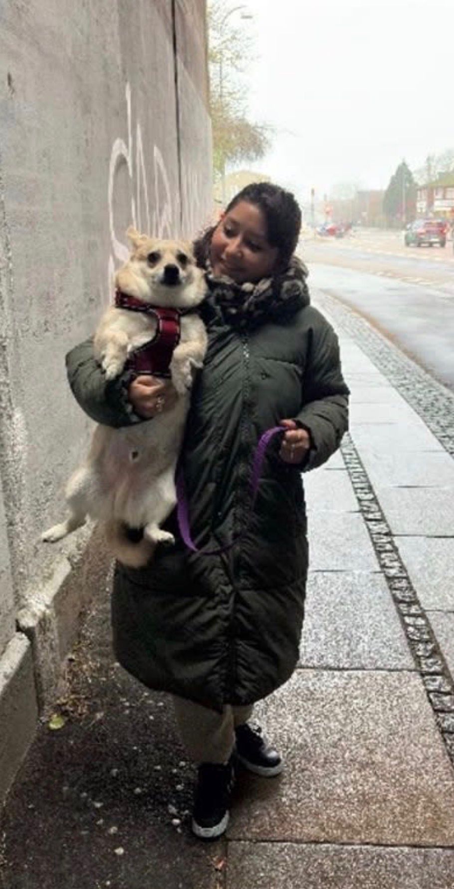 Sofia holding a small dog on a city street