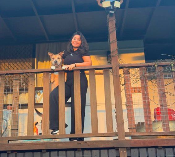 Sofia with a pit bull on a balcony at dusk